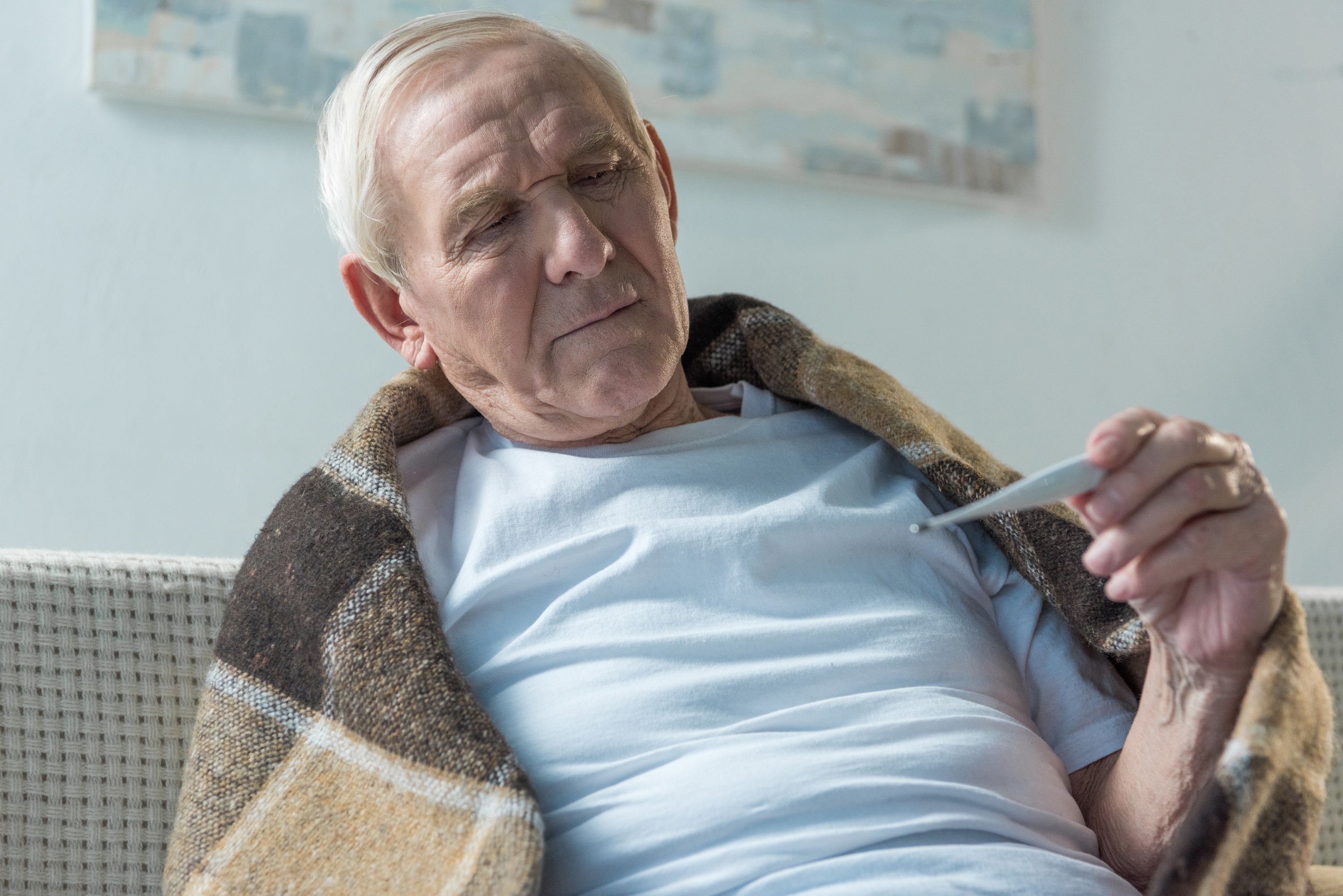 senior sick man looking at thermometer 