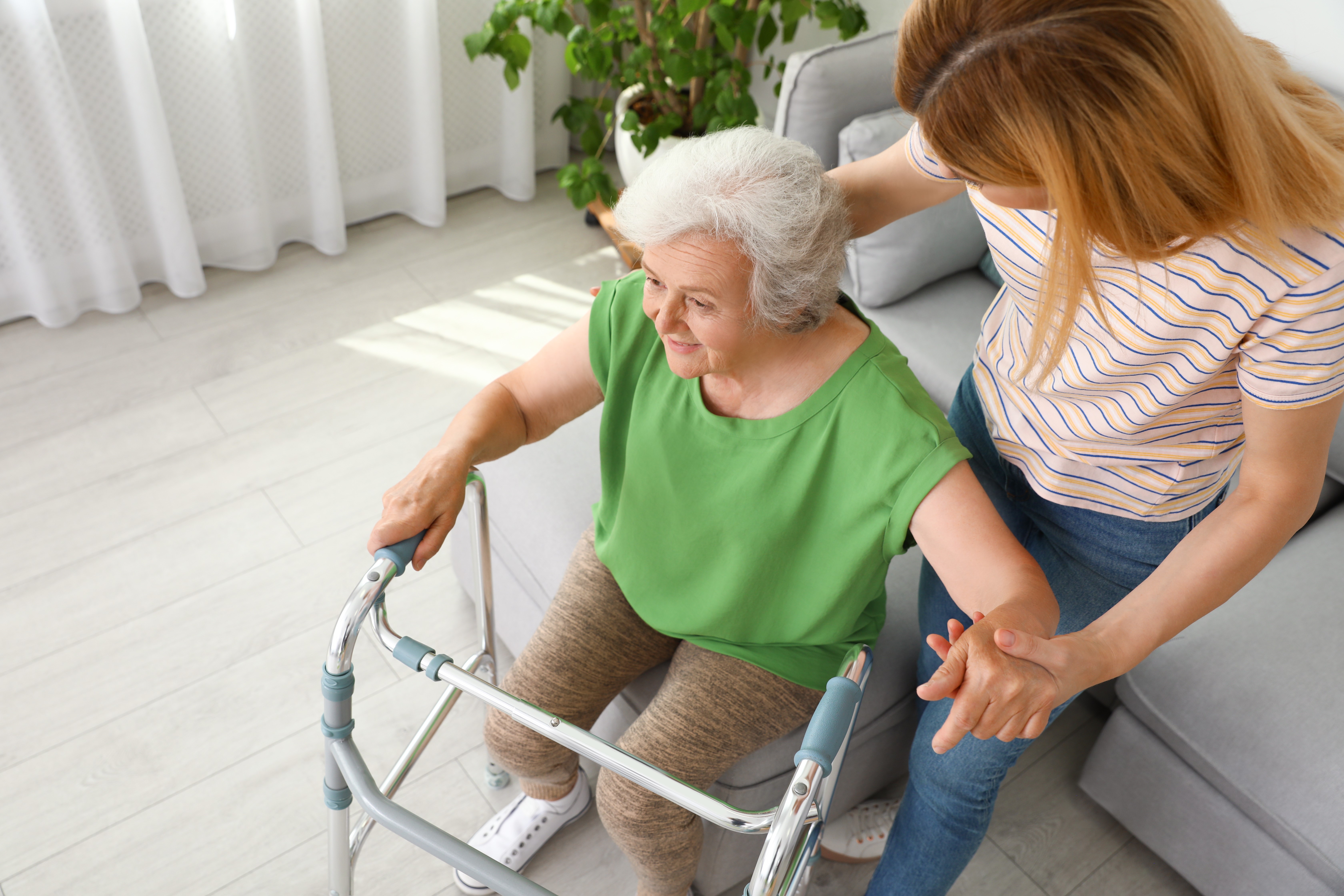 Young women helping older women with a walker