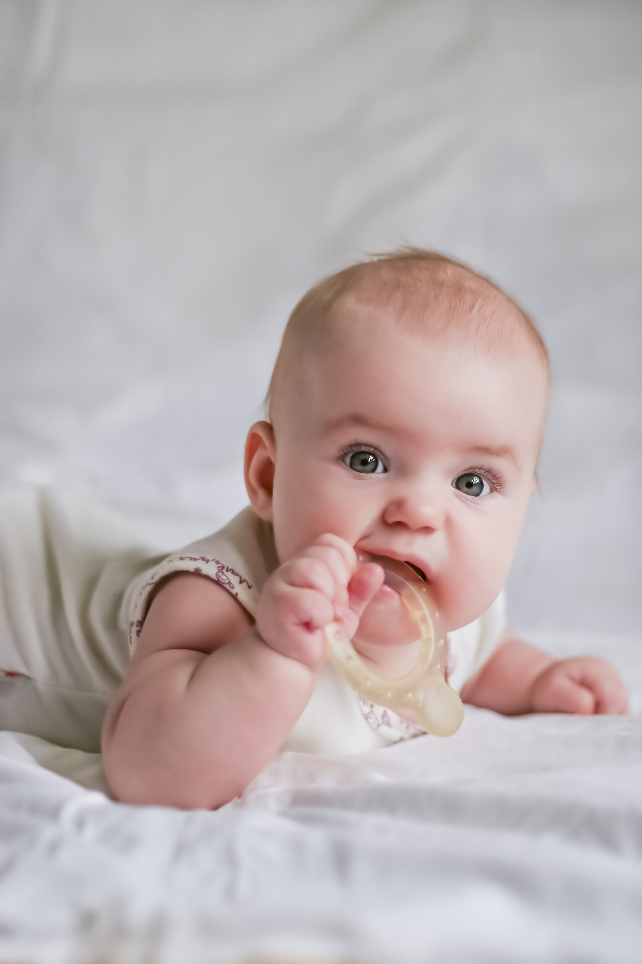 Baby laying on its tummy with a teething toy. 