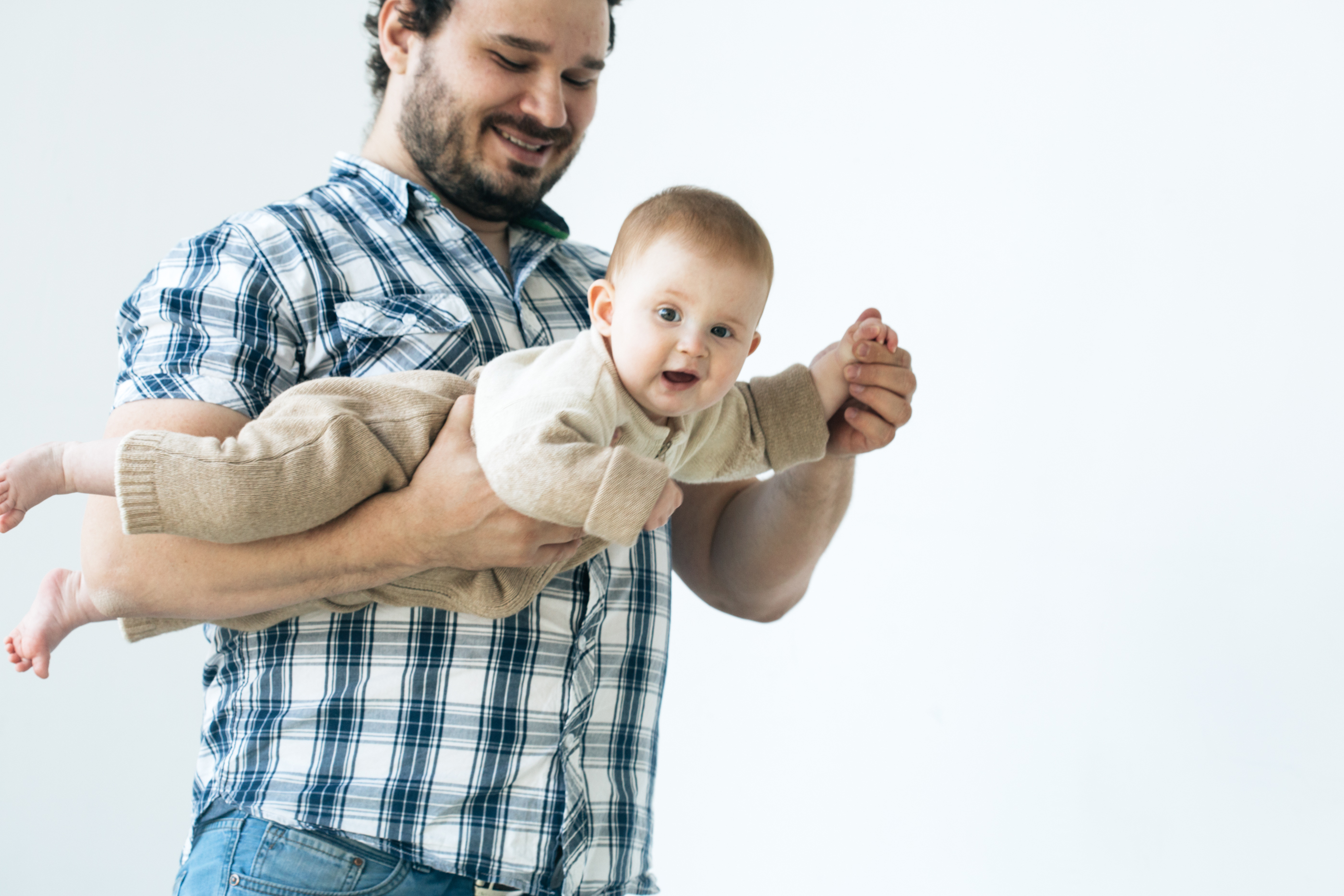 Father carrying a baby on its tummy. 