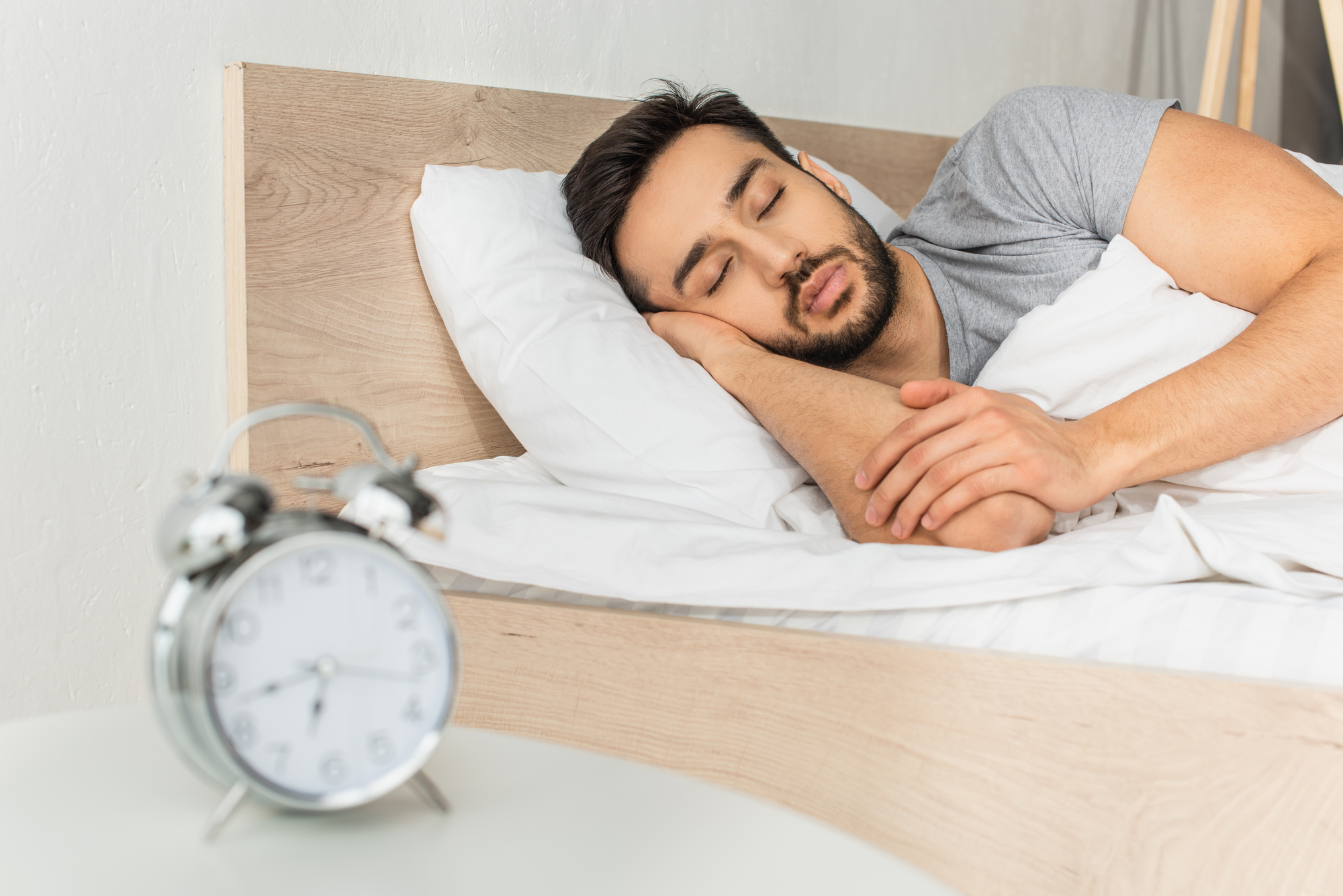 man sleeping next to alarm clock