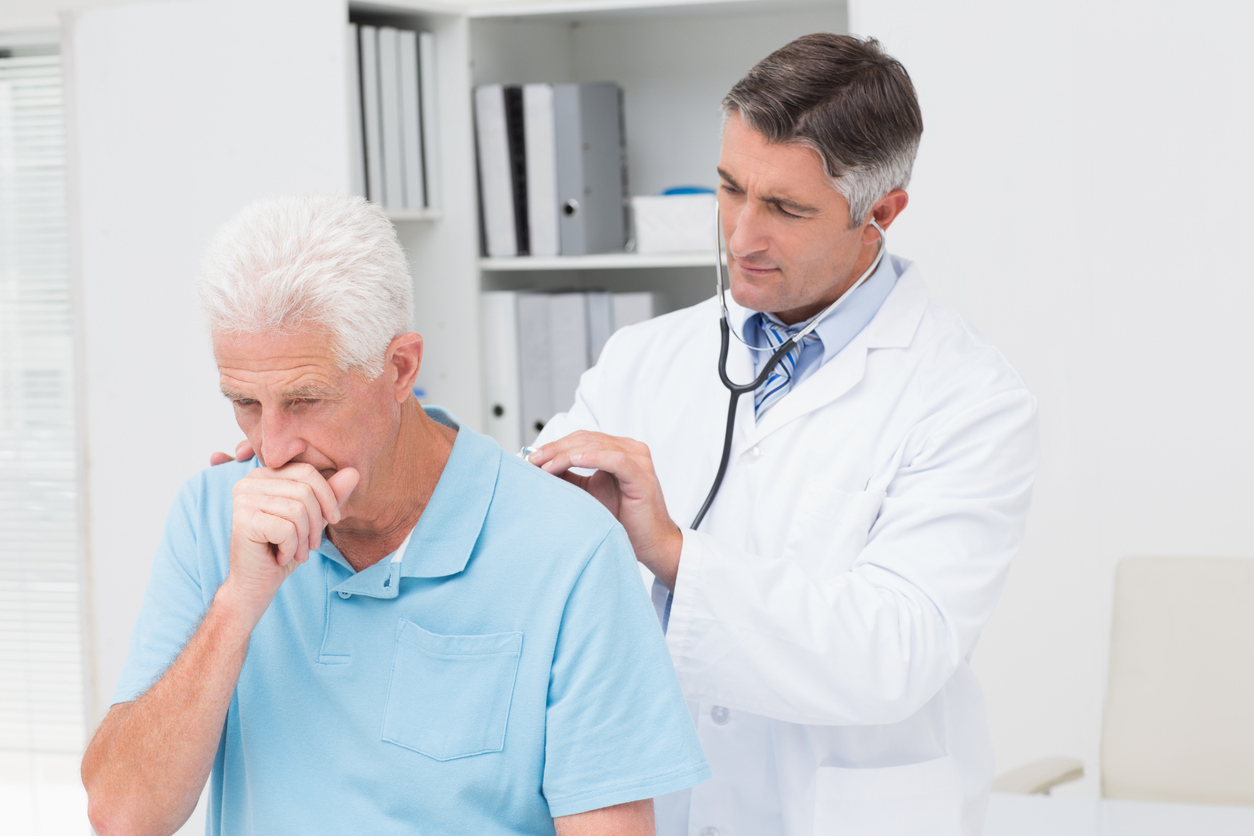 elderly man coughing while doctor checks his breathing