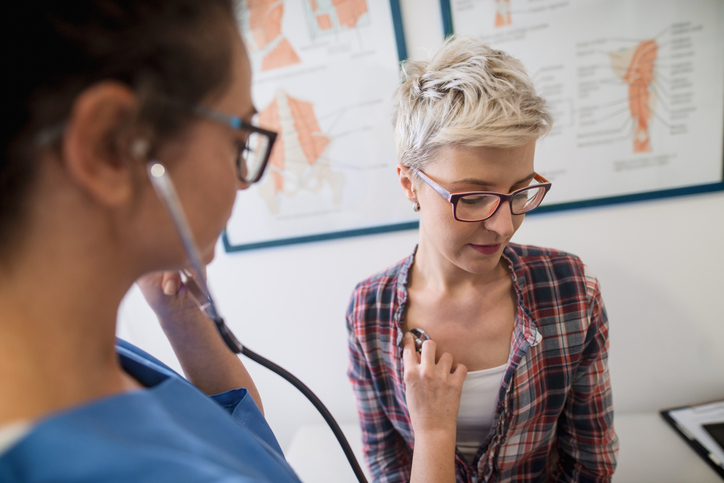Doctor with stethoscope listens to a woman's heart