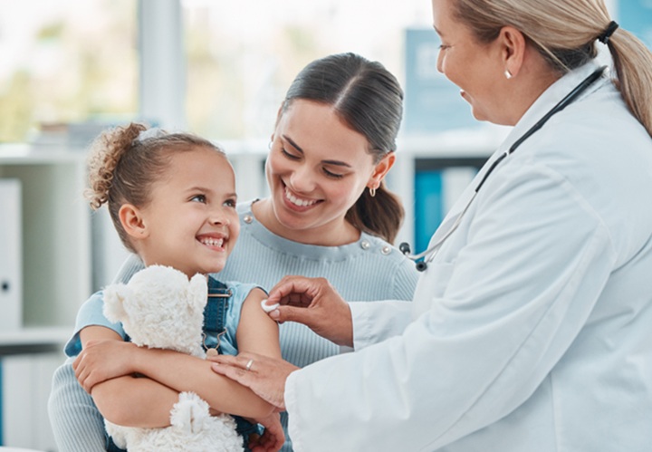 Little girl in mom's lap gets vaccinated by a provider