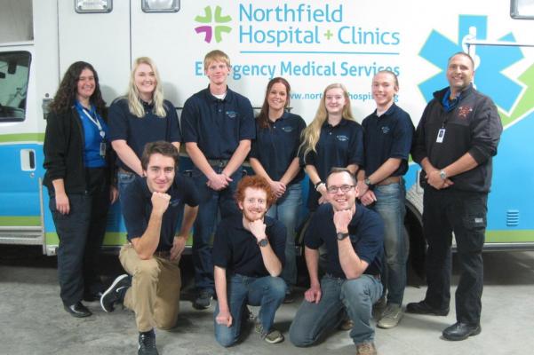 A class of students smiling in front of an ambulance