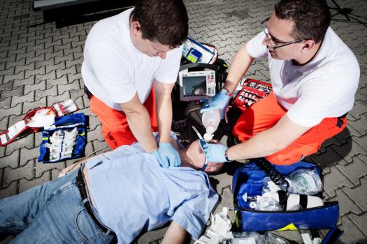Two emergency medical technicians working on patient