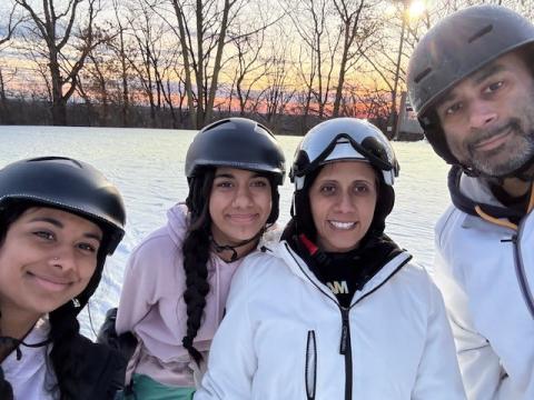 Mukti Patel with husband and two daughters smile from the ski slope where they're skiing together.